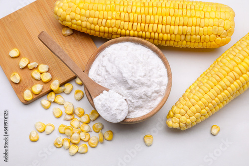 Bowl with corn starch, ripe cobs and kernels on white marble table, flat lay photo