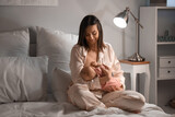 Young woman breastfeeding her baby in bedroom at night