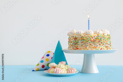 Принти на полотні Stand with yummy Birthday cake, party cones and meringue on color background