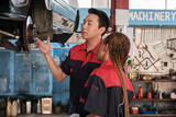 Professional automotive supervisors inspect and discuss car suspension repair work with female African American mechanic worker at service garage, and fix specialist occupations in the auto industry.