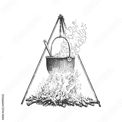 A campfire cooking pot hanging on a tripod on the top of a bonfire