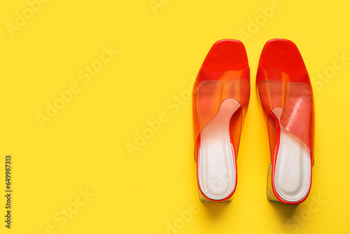 Stylish orange sandals on yellow background