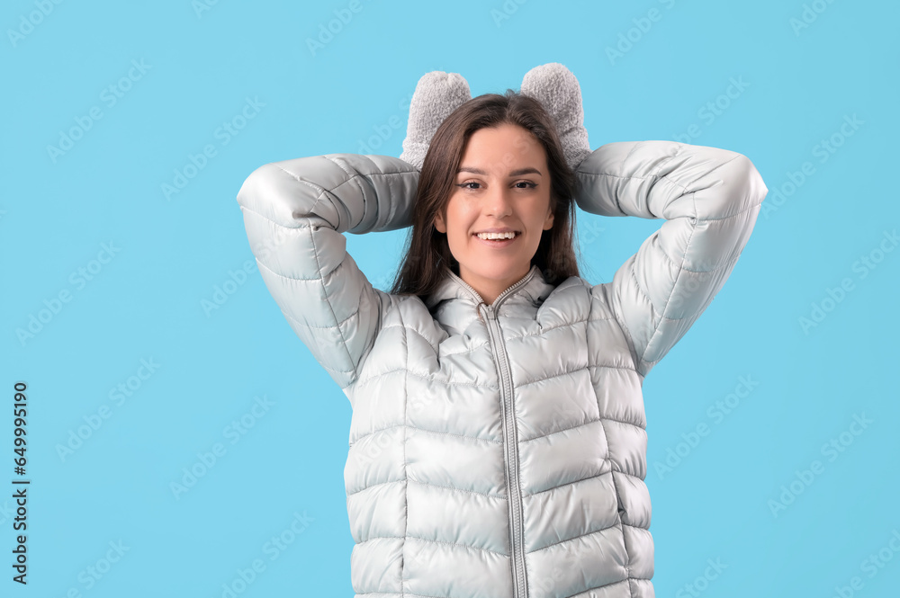 Young woman in winter clothes on blue background Young woman in winter clothes on blue background