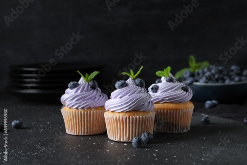 Fototapeta Naklejka Na Ścianę i Meble -  Delicious cupcakes with blueberries and mint on black background