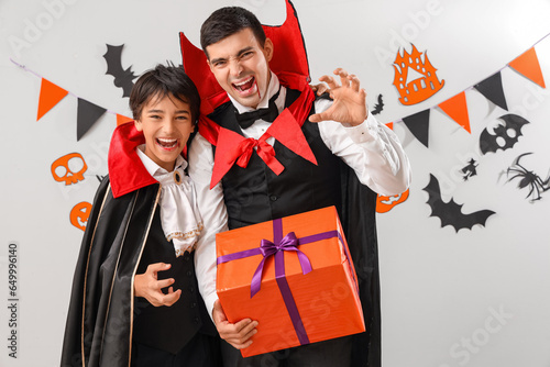 Принти на полотні Little boy and his father dressed for Halloween as vampires with gift on light b
