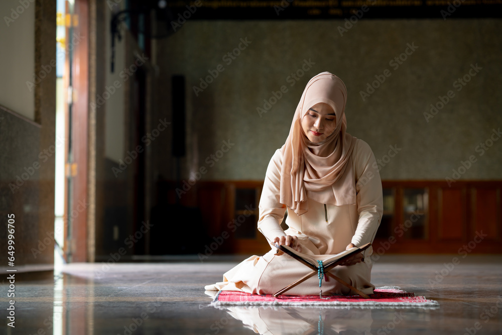 The image of an Asian Muslim woman in the Islamic religion in hijab in cream color. Sitting reading the Quran and having a happy smiling face Staying in a beautiful mosque out of respect for God.