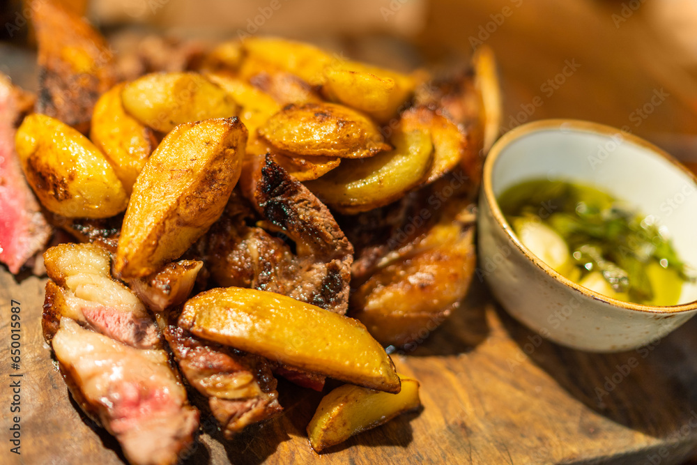 Baked potato wedges with steak and sauce on wooden desk, dish in restaurant Baked potato wedges with steak and sauce on wooden desk, dish in restaurant