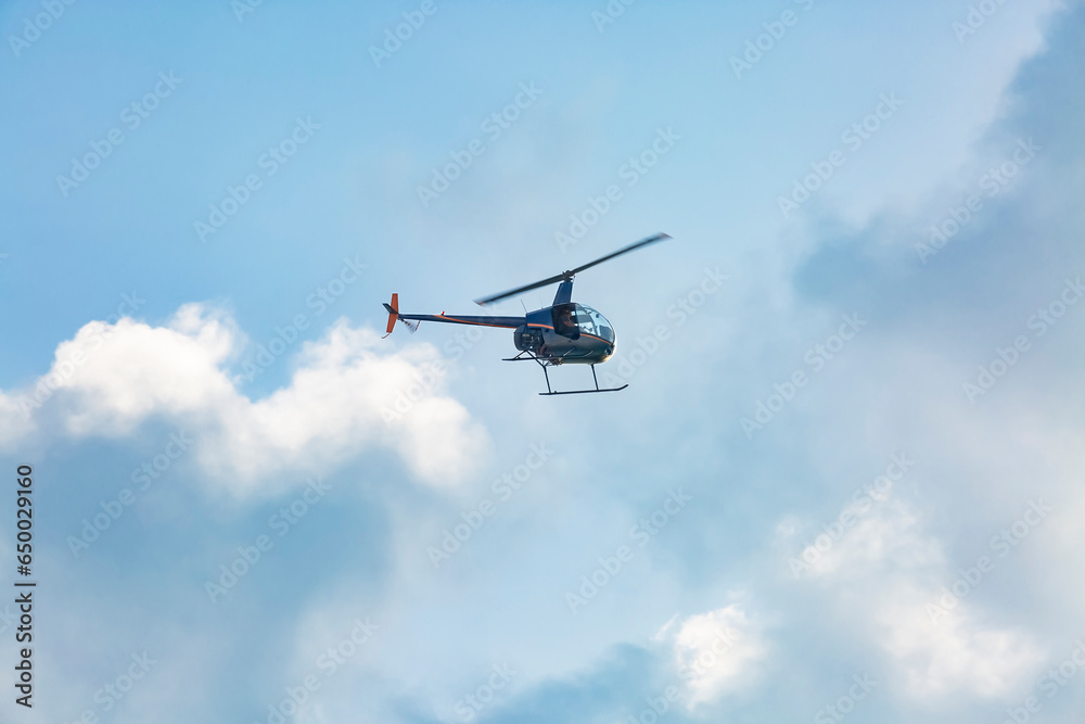 A small helicopter flies through the cloudy sky A small helicopter flies through the cloudy sky