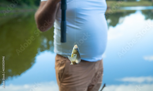 Man catching and showing small fish in the lake.