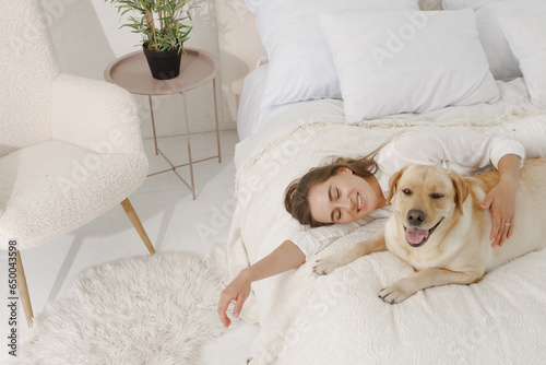 girl in white clothes with dog labrador playing at home