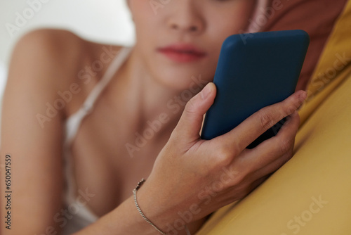 Closeup image of young woman checking social media on smartphone after waking up in the morning photo