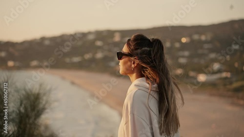 Beautiful Lady Wearing Sunglasses Walking To Watch Sunset In Cool Wind photo