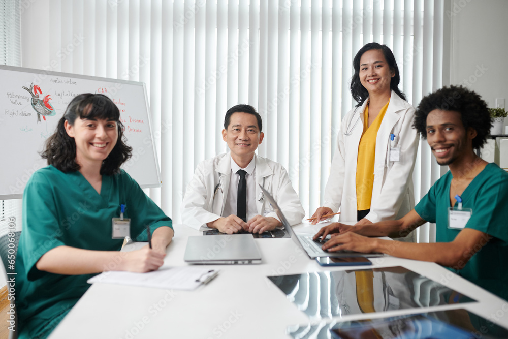 Happy medical team sitting at big table in office of clinic Happy medical team sitting at big table in office of clinic