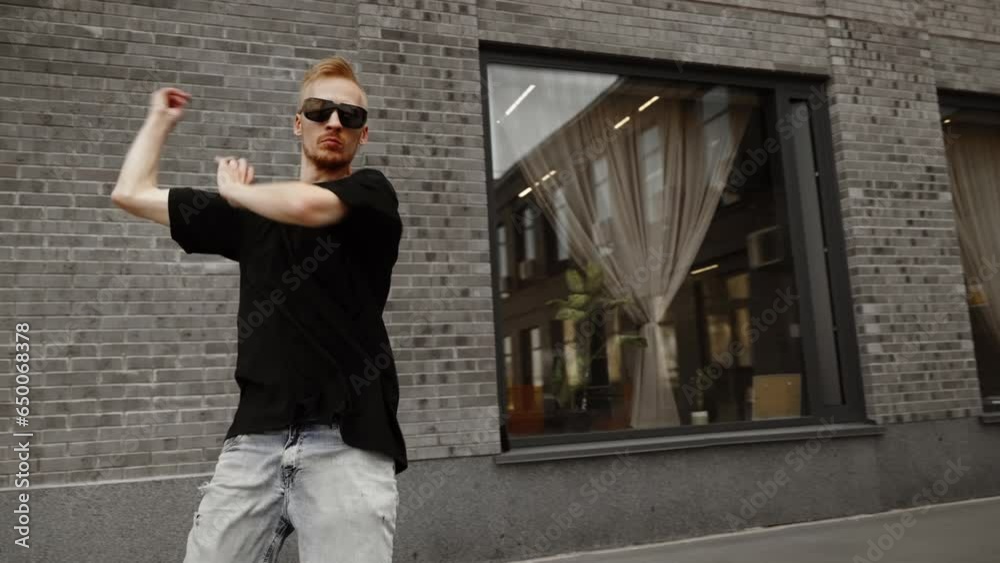 The dancer is actively moving against the background of the gray wall of the house. Modern dance. Active camera. Retarded motion. The dancer is actively moving against the background of the gray wall of the house. Modern dance. Active camera. Retarded motion.