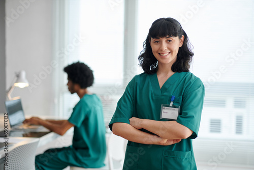 Portrait of smiling medical nurse in green scrubs crossing arms and looking at camera photo