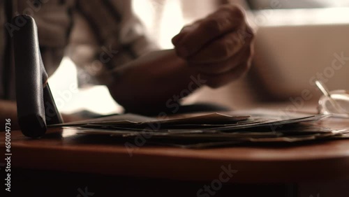 hands of a pensioner holding and looking at family black and white photos while at home. concept nostalgia, family photos, emotions of old people