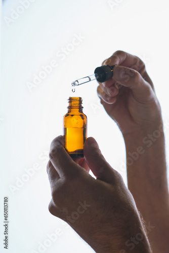 Crop person with bottle of serum