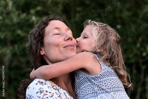 maman et fille partageant des moments authentiques et des bisous en plein air photo