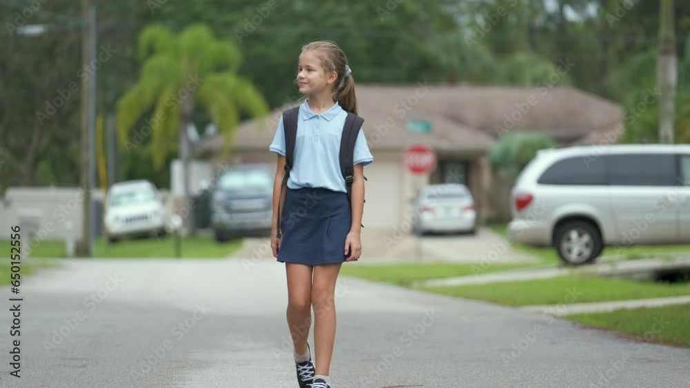 Young student girl walking on suburban street returning home from school Young student girl walking on suburban street returning home from school