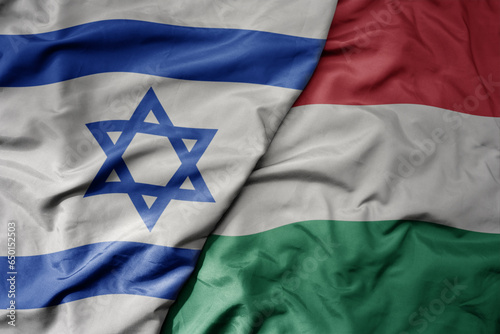 big waving national colorful flag of israel and national flag of hungary . photo