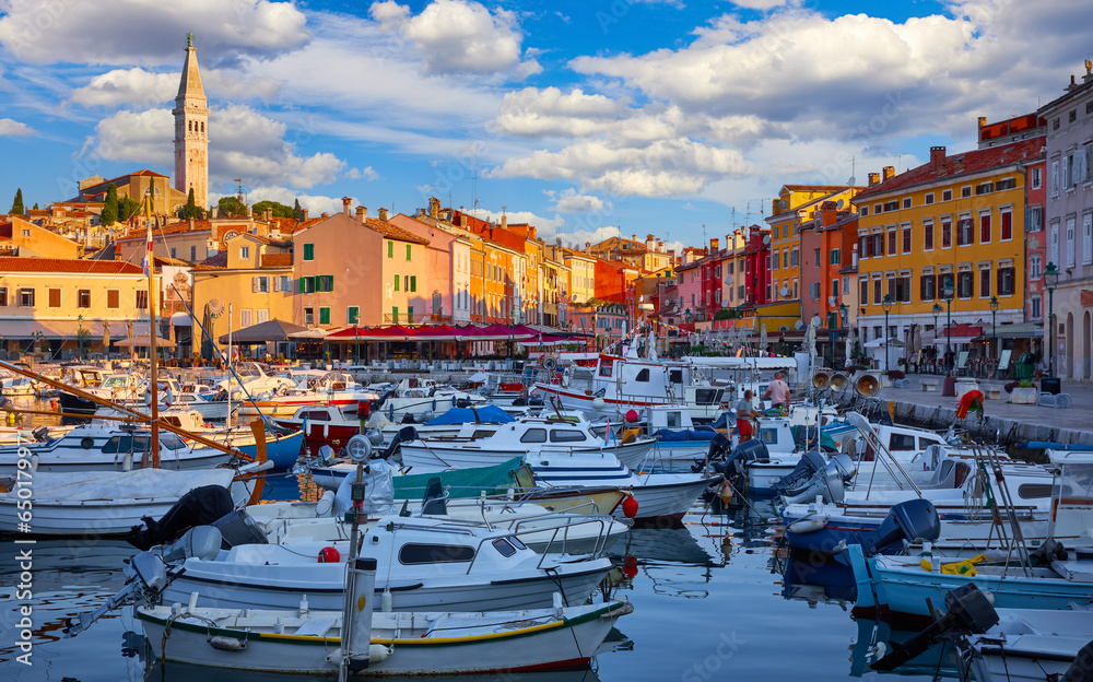 Rovinj, Croatia. Motorboats and boats on water in port of Rovigno. Medieval vintage houses rovinj old town. Yachts landing, tower with clock. Morning sunrise Istria. Blue sky clouds
