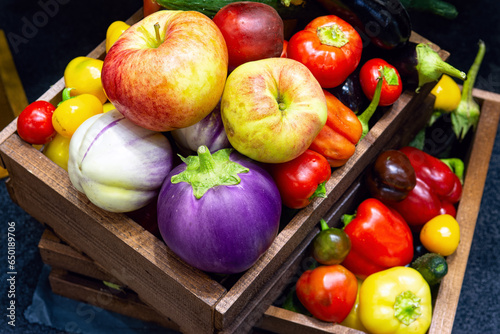 Various fruits and vegetables in wooden boxes top view. Ripe apples, tomatoes, peppers, various eggplants. Fresh fruits and vegetables from your own garden.