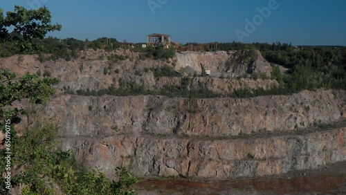 Beautiful granite quarry during the day. Lots of stones. Stones overgrown with trees and grass. Trees sway in the wind. Top view of the stone quarry.