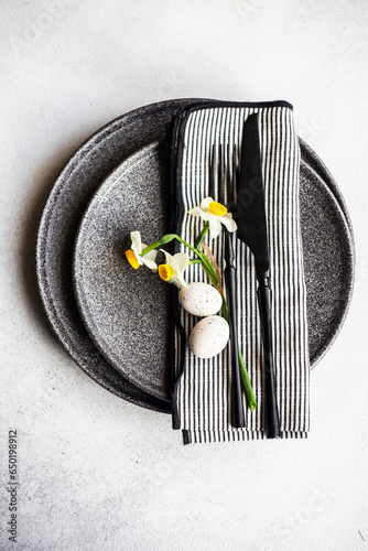 Place setting for Easter festive dinner with daffodil flowers and eggs on concrete background photo