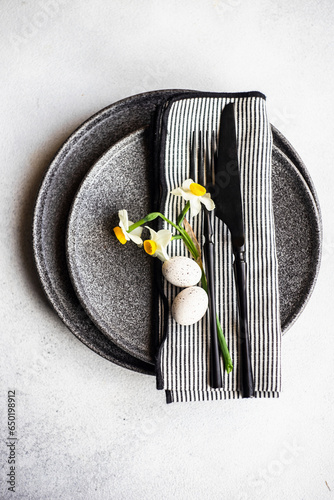 Place setting for Easter festive dinner with daffodil flowers and eggs on concrete background