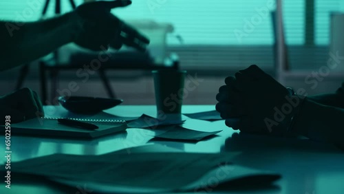 Close up detail video of the hands of a suspect, offender, perpetrator or prisoner and a detective, policeman sitting in the interrogation room, discussing the case. photo