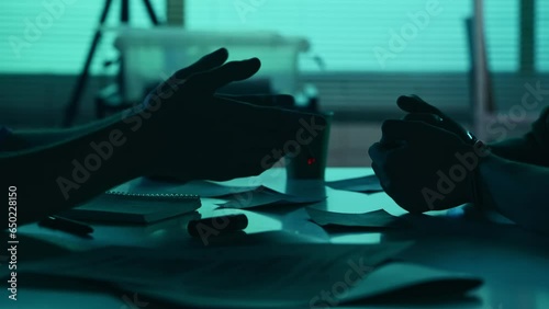 Close up detail video of the hands of a suspect, offender, perpetrator or prisoner and a detective, policeman sitting in the interrogation room, discussing the case. photo