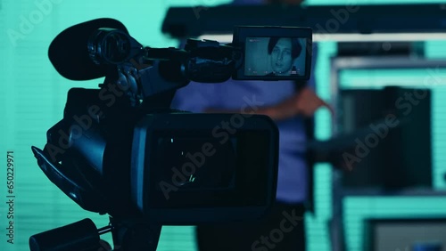 Close up detail video of the camera filming, recording the face of a suspect, offender, perpetrator or prisoner talking to a detective, policeman standing on the background. photo