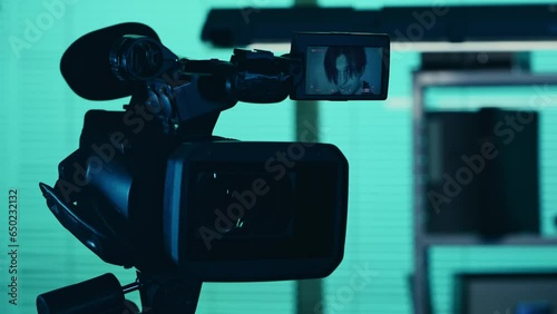 Close up detail video of the camera filming, recording the face of a suspect, offender, perpetrator or prisoner talking to a detective, policeman standing on the background. photo