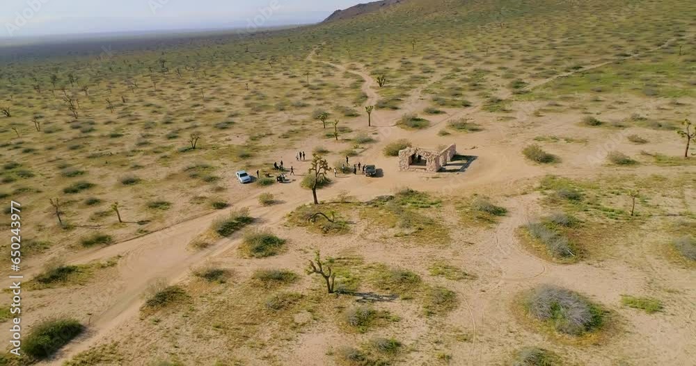 Aerial Panning Shot Of People By Cars Near Structure Amidst Plants During Sunny Day - Joshua Tree, California