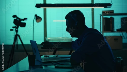 Medium silhouette video of a detective, policeman sitting in the interrogation room, smoking, studying the evidence and drinking coffee. The man looks exhausted and disappointed. photo