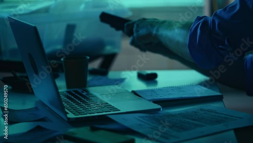Close up detail silhouette video of a detective, policeman sitting in the interrogation room, working on a laptop and studying the evidence. photo