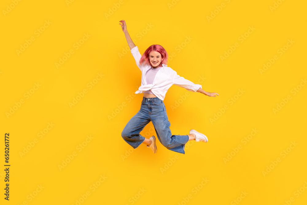 Glad lady student in casual with pink hair jumping and freezing in air, having fun on yellow background, full length