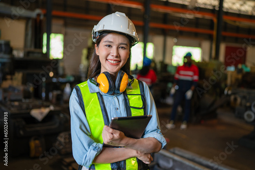 Portrait of female engineer standing and using tablet in modern industrial factory, Woman looking camera in industrial factory.