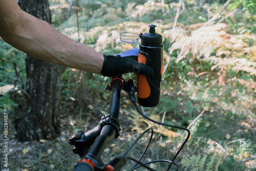 Travel by bike.A cyclist's gloved hand in close-up with a bottle of water.An active lifestyle.Mountain Bike