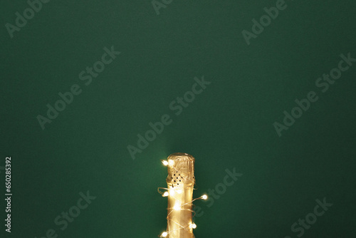 Champagne bottle with garlands on color background © fotomaximum