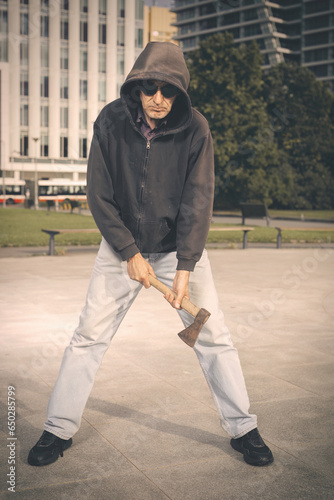 Aggressive older man with axe under the influence of drugs in park photo