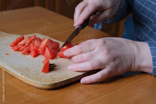 An elderly woman's hands hold a tomato