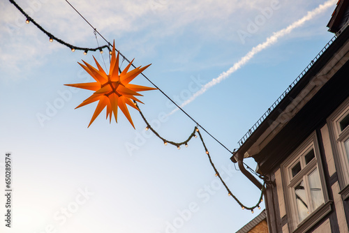 Beautiful Moravian star or Herrnhuter Stern street glowing decoration hanged on wall german city street at christmas advent winter holidays. Traditional Xmas ornament decor in Germany