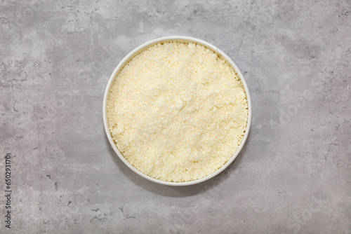 Top view of a bowl with grated Mexican Cotija cheese for food garnishing.