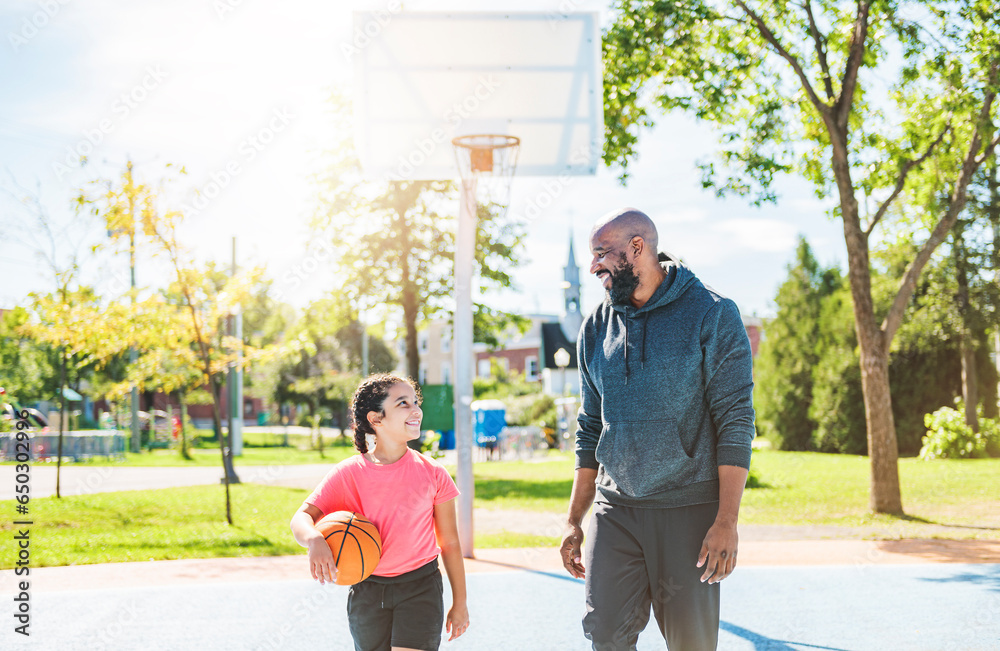 father and daughter playing basketball in the park