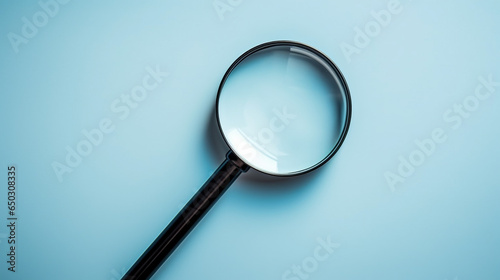 Black magnifying glass with light blue background. Top view, copy space background, business concept. photo