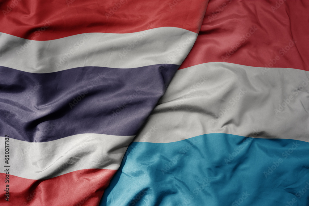 big waving national colorful flag of thailand and national flag of luxembourg .