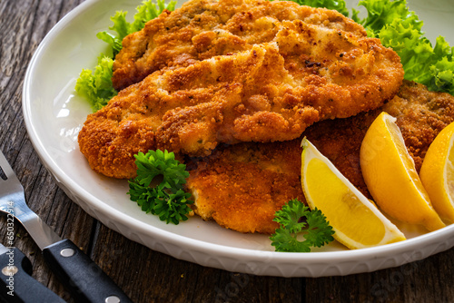 Photography Crispy breaded seared chicken cutlet with lemon slices and fresh vegetables on w