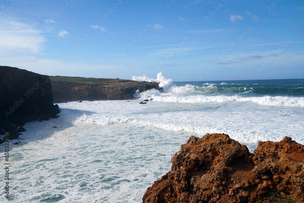 big waves rolling and breaking against cliff with high fountain of splashing water big waves rolling and breaking against cliff with high fountain of splashing water