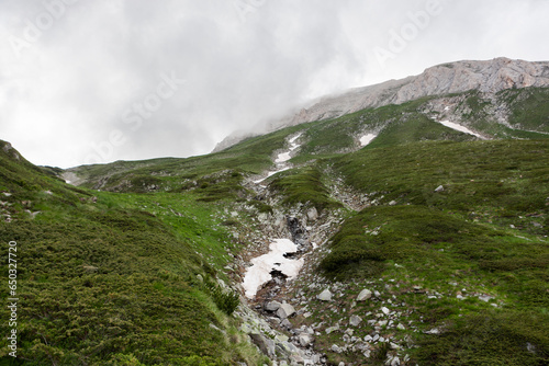 Green mountain slope on cloudy day. Landscape on trekking trail to Vihren peak. Pirin National Park in Bulgaria.